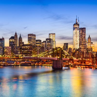 New York City, USA skyline over East River and Brooklyn Bridge.